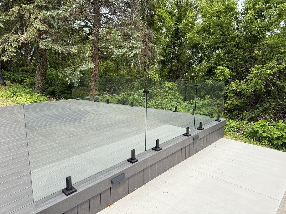 Frameless glass deck railing surrounded by trees